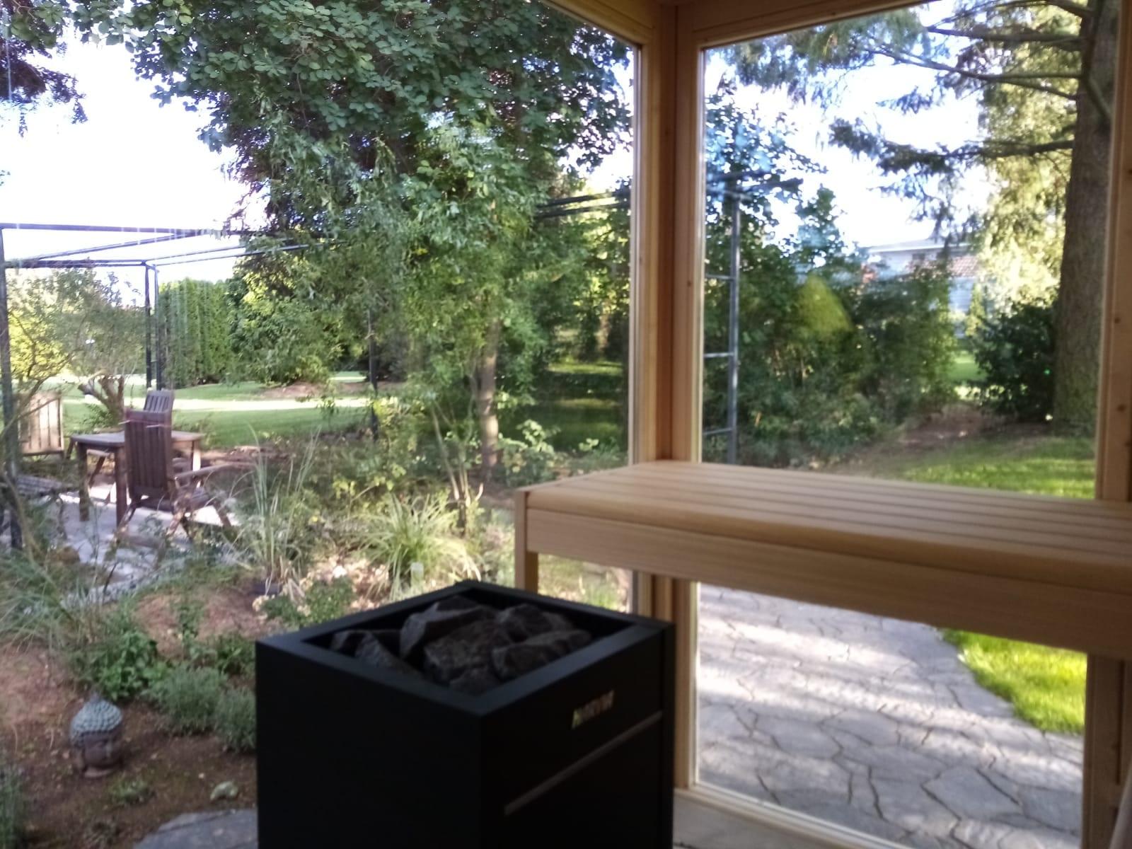 Blick aus der Tirano Gartensauna mit Saunaofen in den Garten