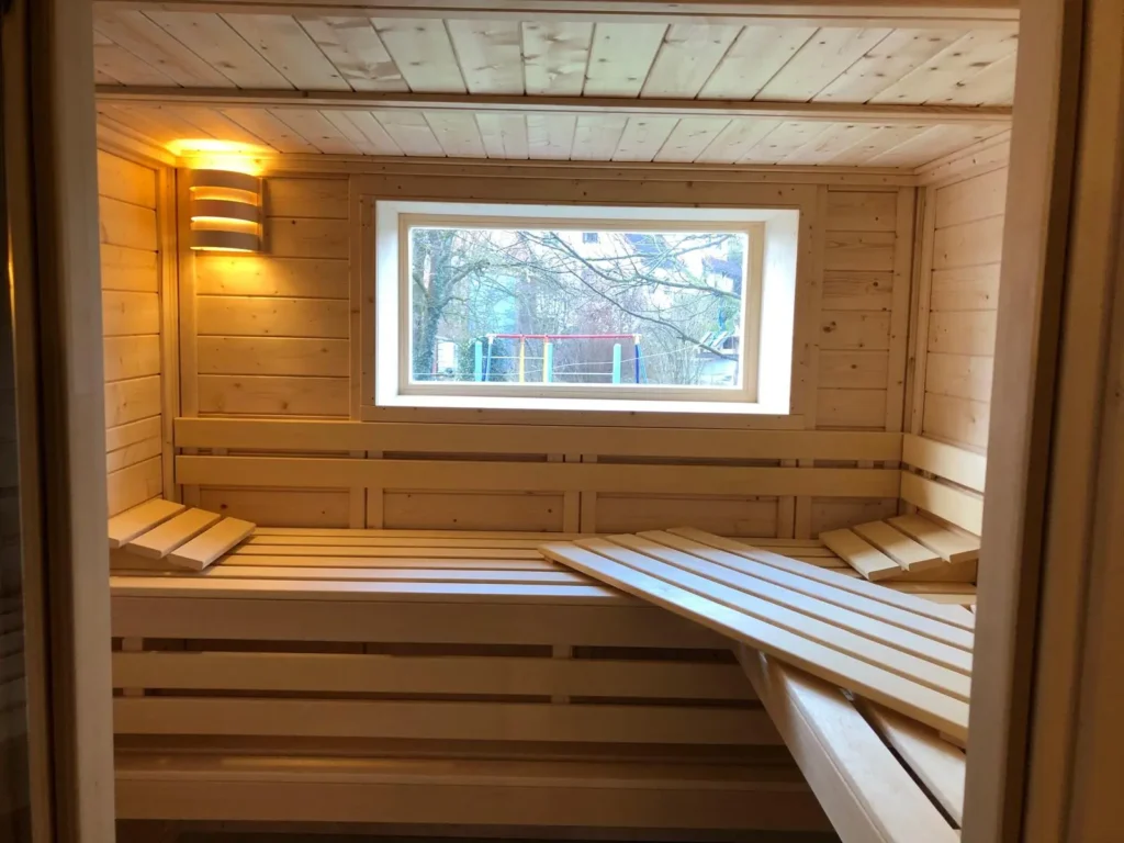 Gemütliche Bormio Massivholzsauna aus hellem Fichtenholz mit integriertem Fenster, klassischen Saunabänken und natürlicher Wellness-Atmosphäre